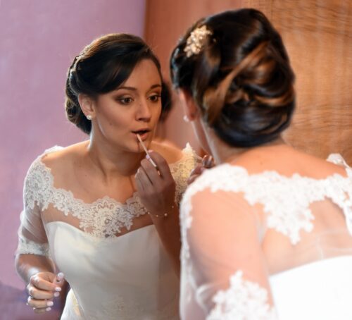 Mariée se maquille et se voit dans un miroir.